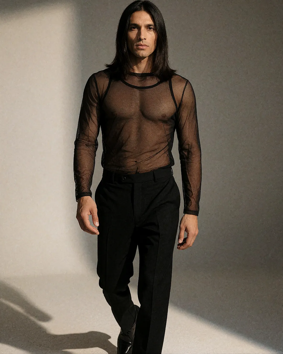 Diego Villalobos trägt ein transparentes schwarzes Mesh-Oberteil mit schwarzer Hose im Studio.