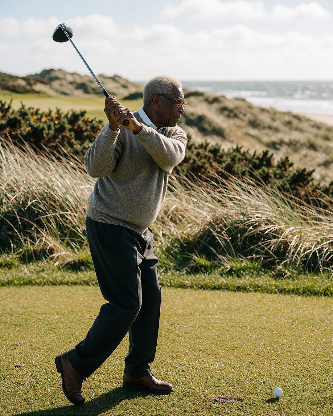 Earl Radcliffe schlägt beim Golf mit Blick auf Küstendünen und das Meer ab.