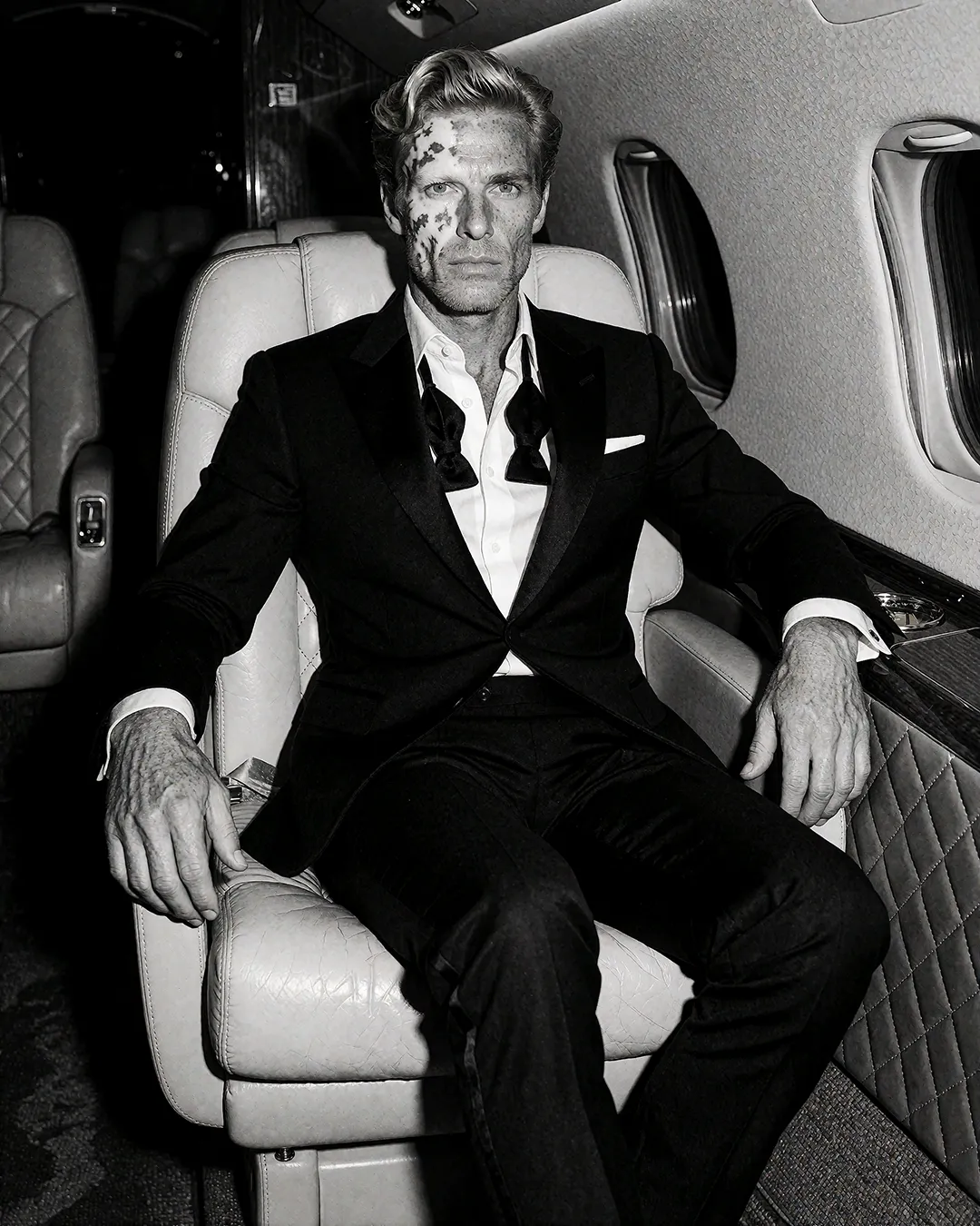 Magnus Thalberg im Smoking sitzend in der Kabine eines privaten Business-Jets